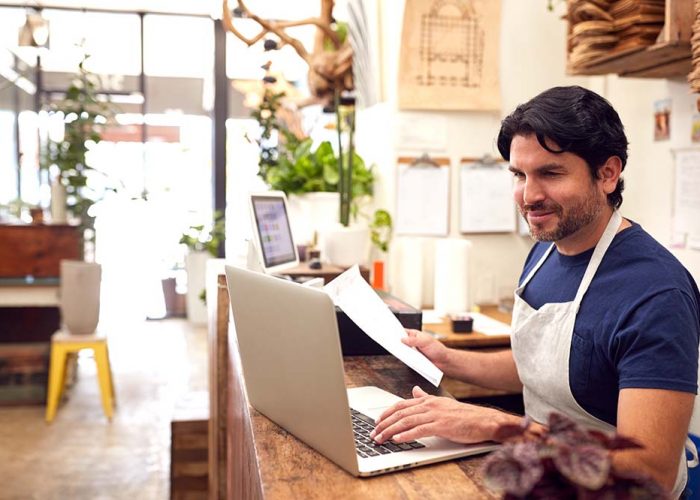 Franquicia Persona en un mostrador revisando una notebook y con papeles en la mano